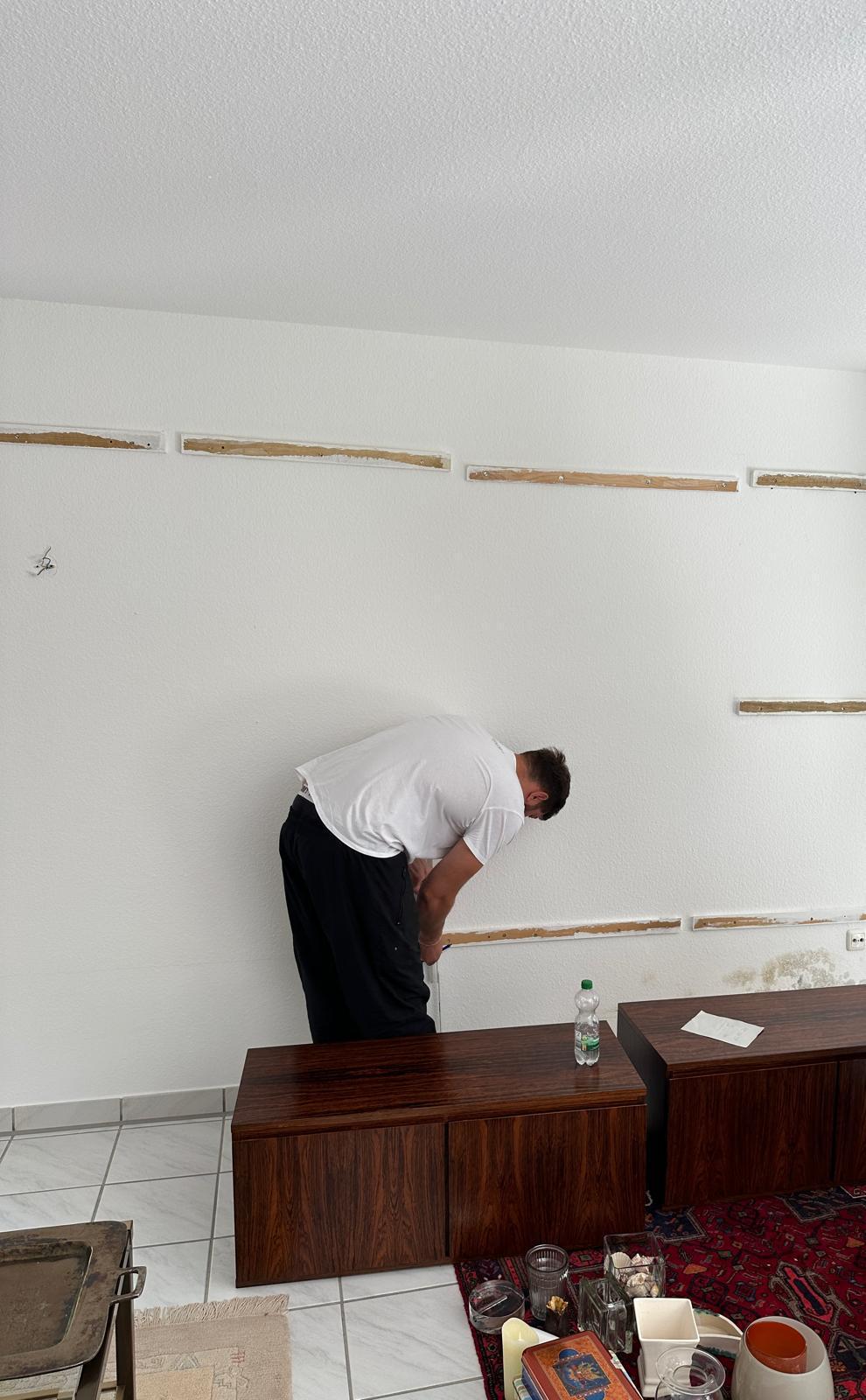 Eine Person arbeitet hinter dem abgebauten Teil einer Schrankwand.