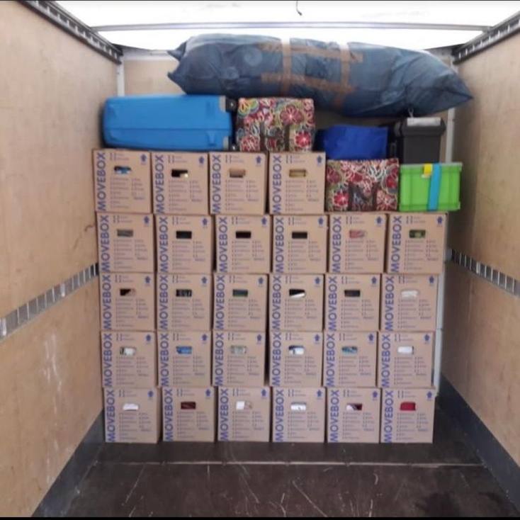 Laderaum eines Umzugswagens: gleich große Umzugskartons, fünf Reihen hoch gestapelt, obenauf Koffer und Taschen.